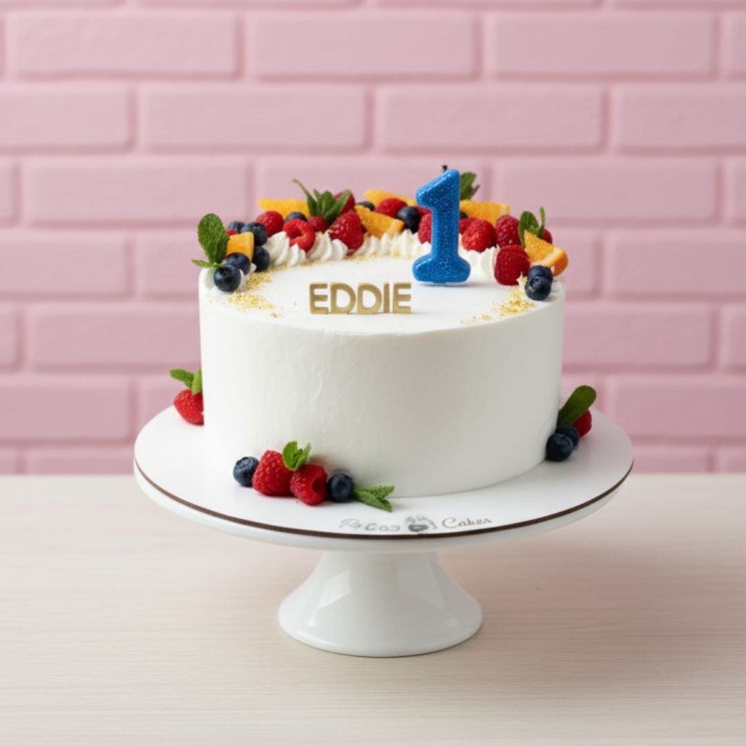 White birthday cake with berries and a number one candle on a pink brick wall background