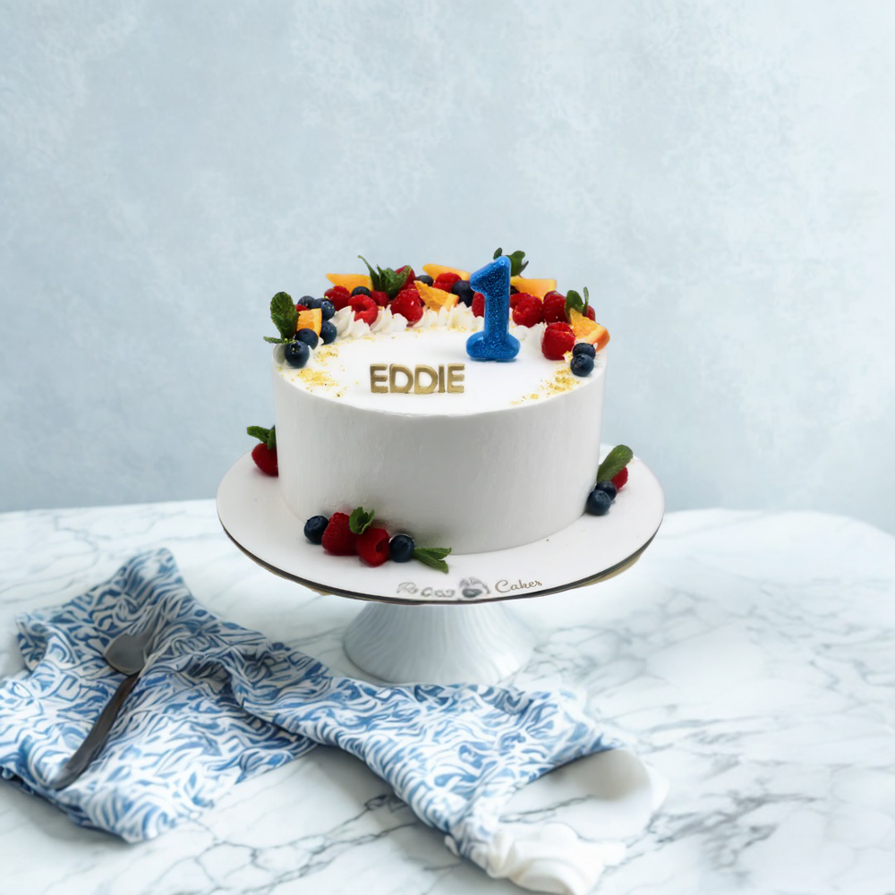 White 1st birthday cake with colorful fruits