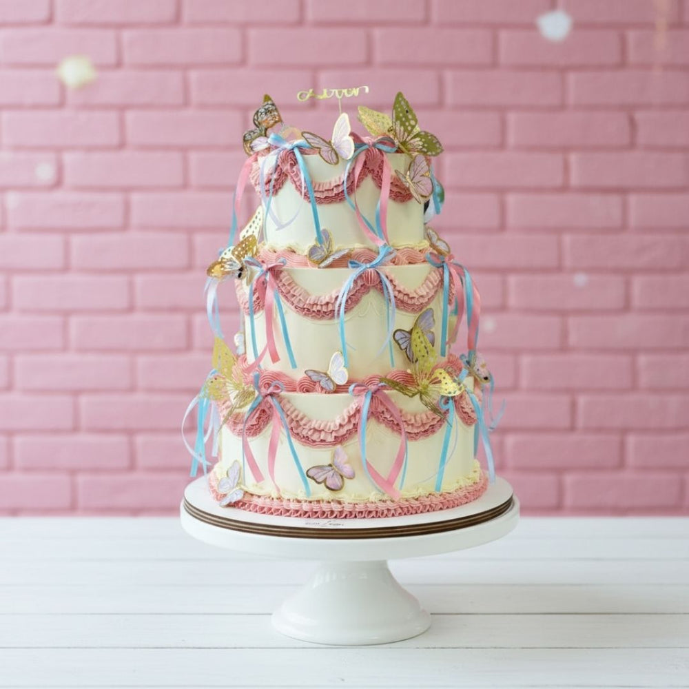 Decorative cake with ribbons and butterflies on a pink brick wall background