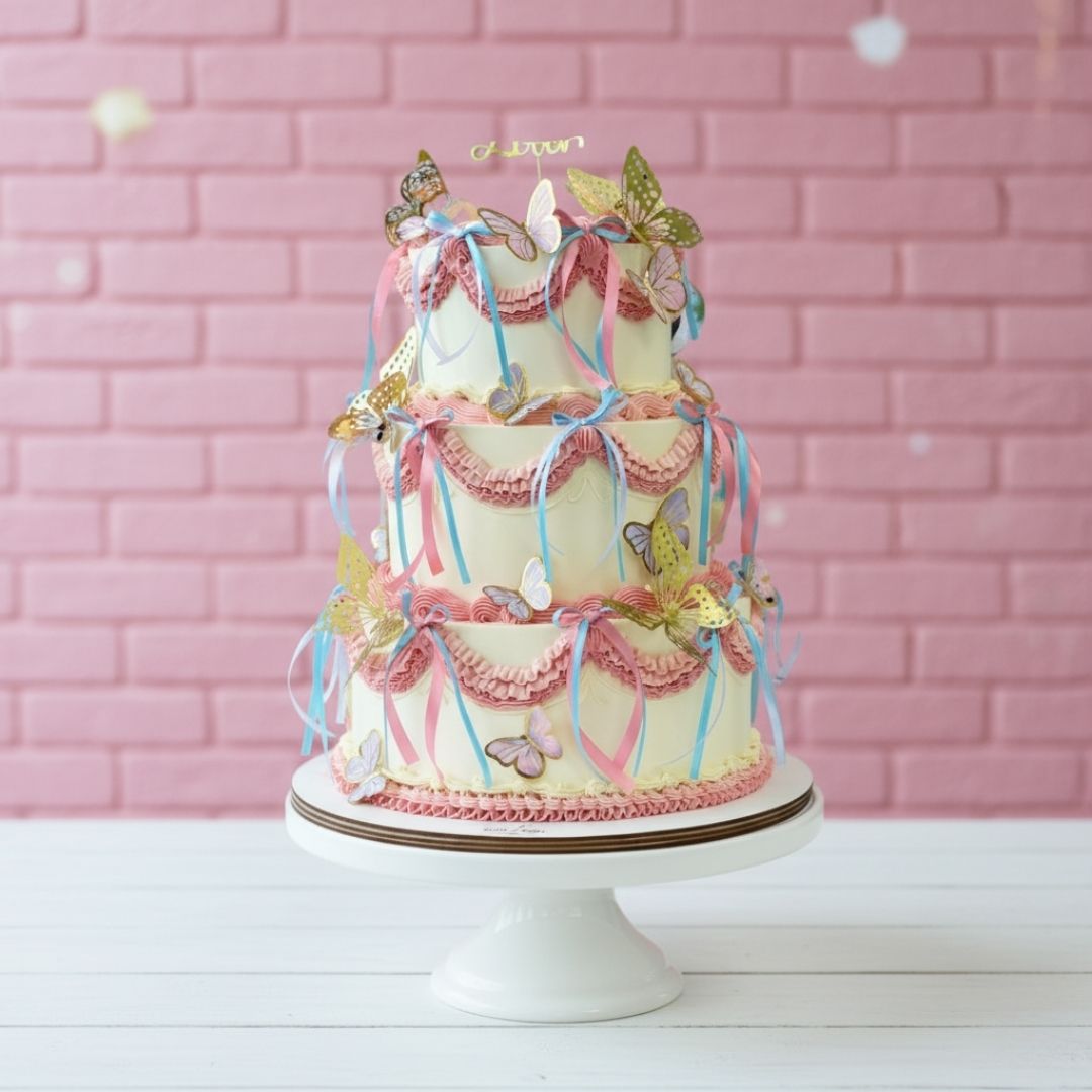 Decorative cake with ribbons and butterflies on a pink brick wall background