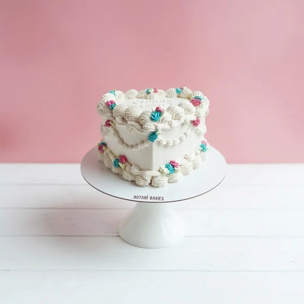 gender reveal cake in heart shape, white colour with blue and pink piping