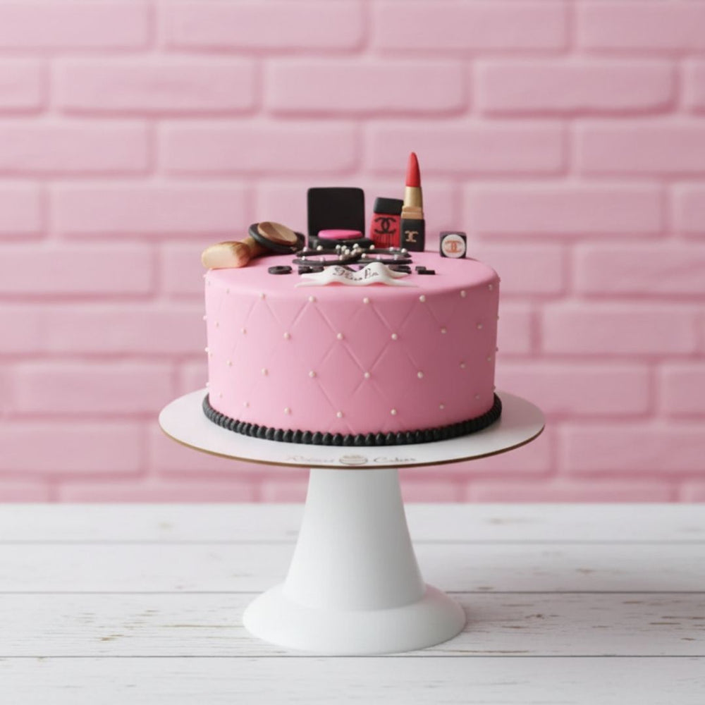 Pink cake with makeup items on a white stand against a pink brick wall.