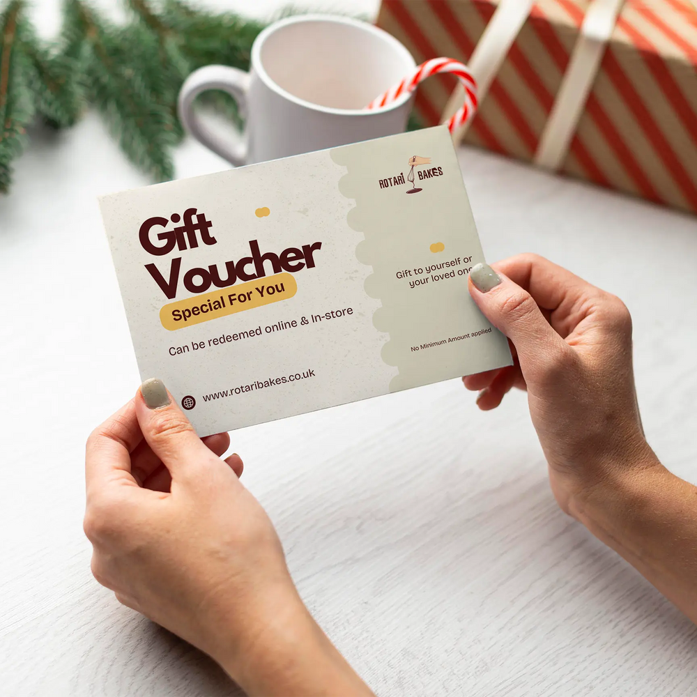 Person holding a gift voucher with a mug and wrapped gift in the background