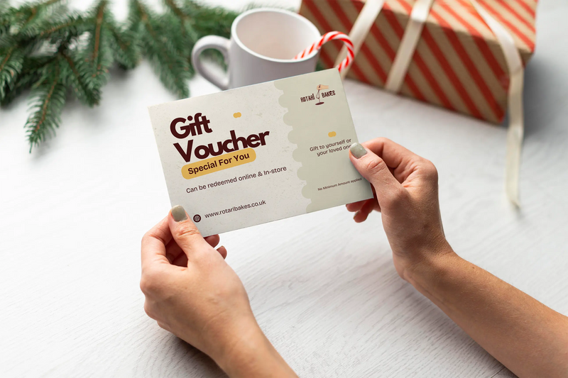Person holding a gift voucher with a mug and wrapped gift in the background