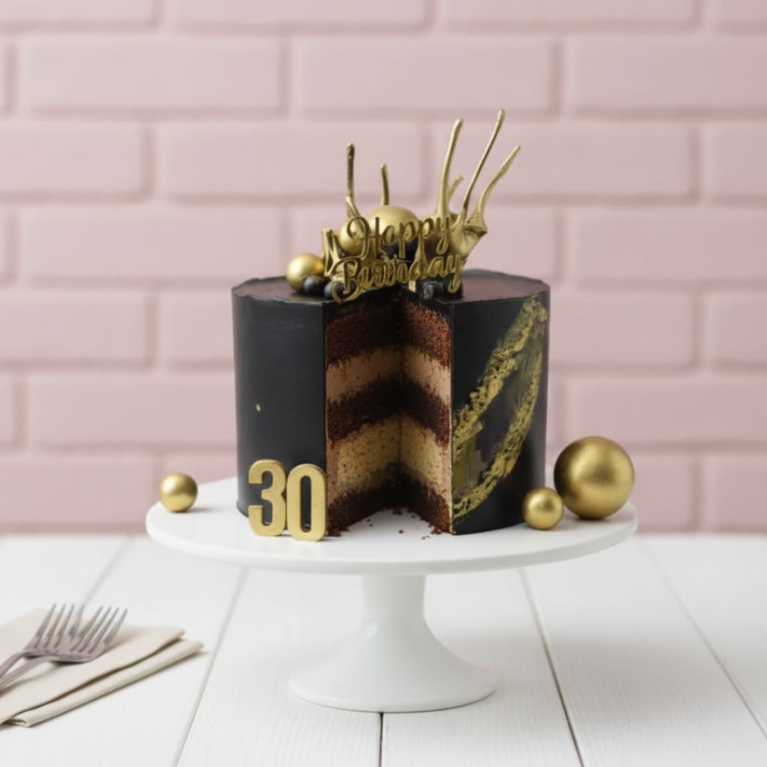 Black and gold birthday cake with 'Happy Birthday' and number '30' on a white stand against a pink brick wall.