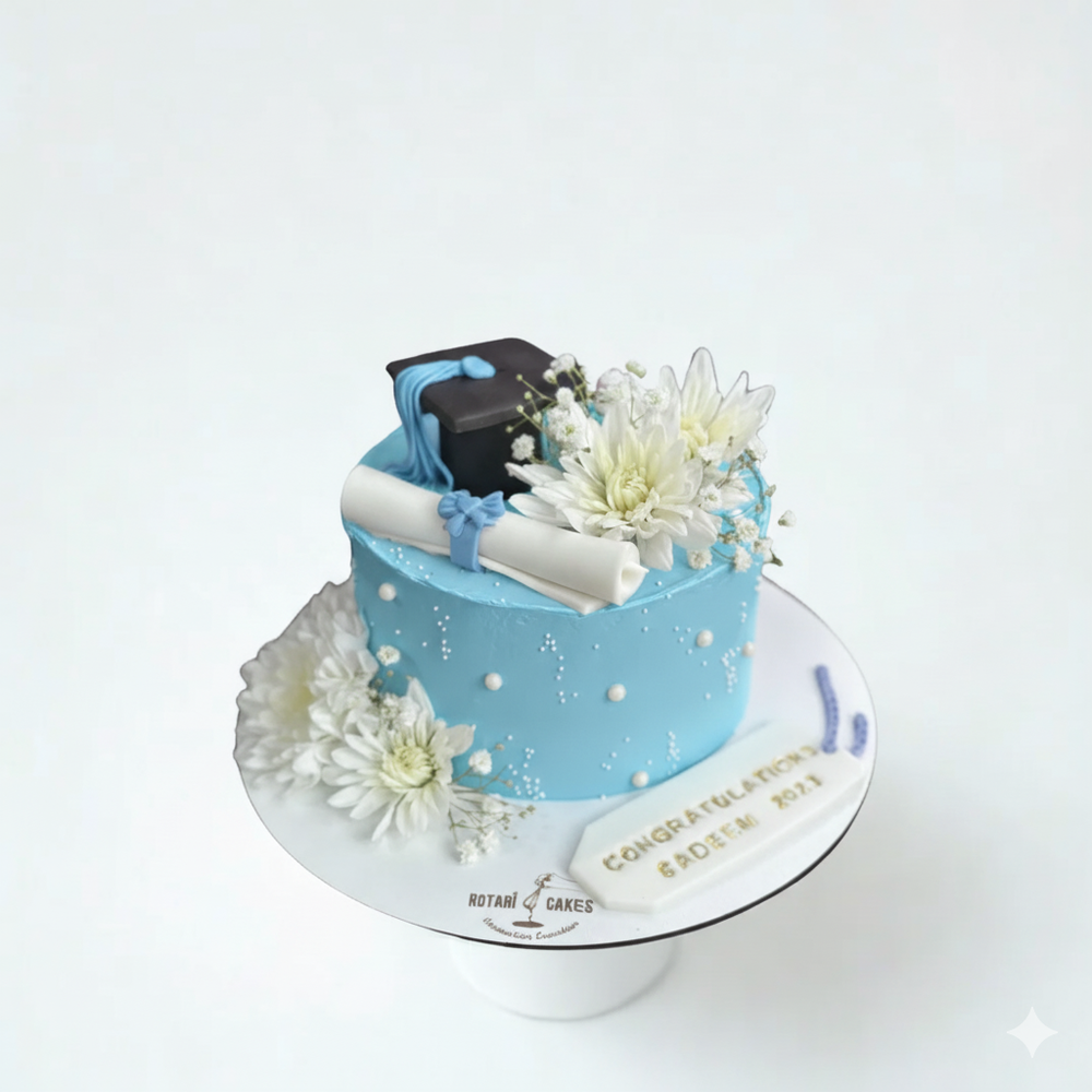 
                  
                    Graduation-themed cake with blue icing, white flowers, and a black graduation cap on a white background.
                  
                