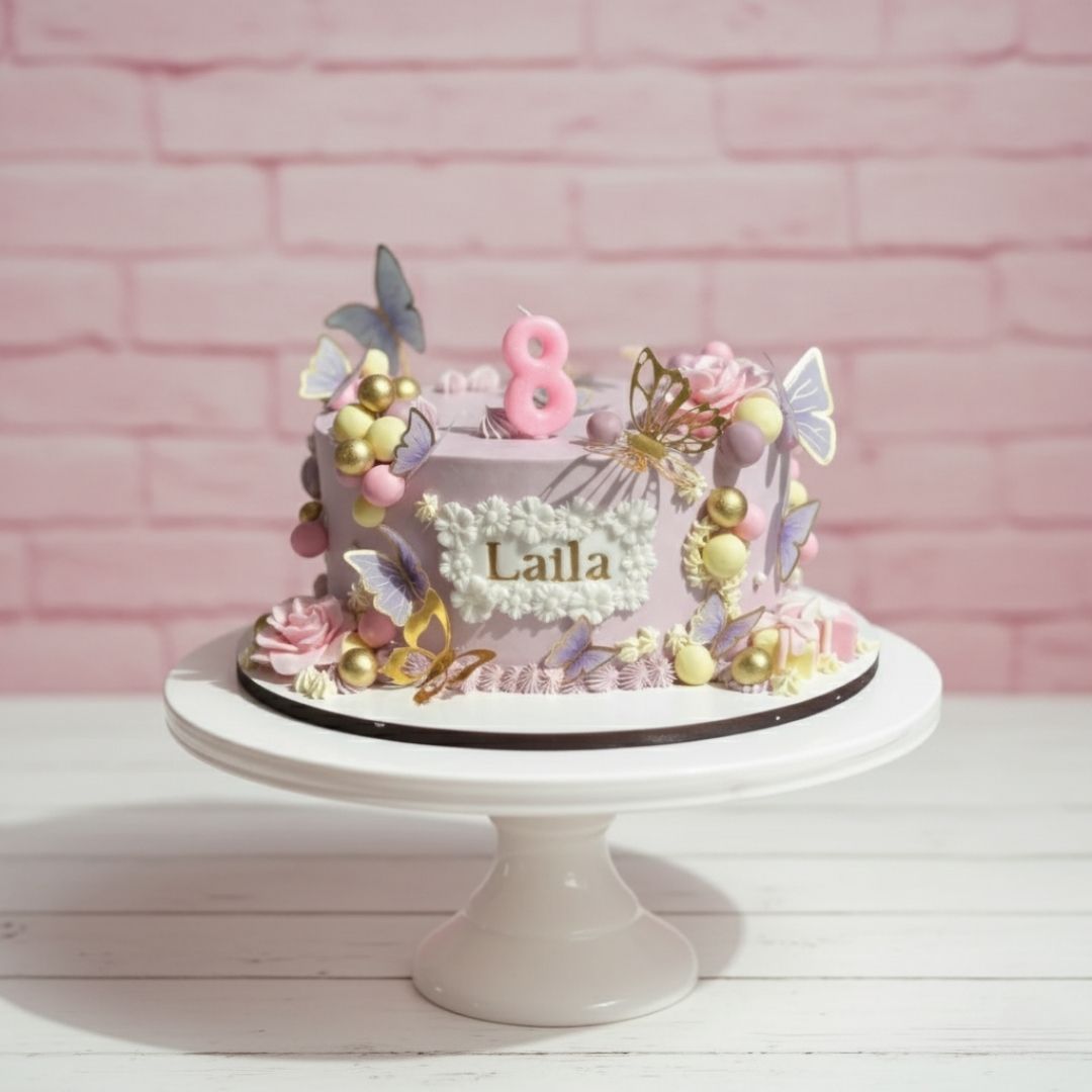 Decorative butterfly theme cake with 'Laila' and number '8' on a pink brick wall background
