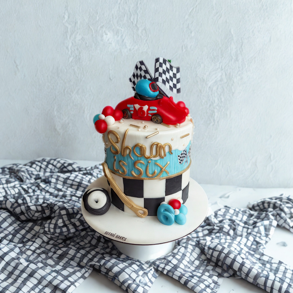 
                  
                    Colorful birthday cake with car-themed decorations
                  
                