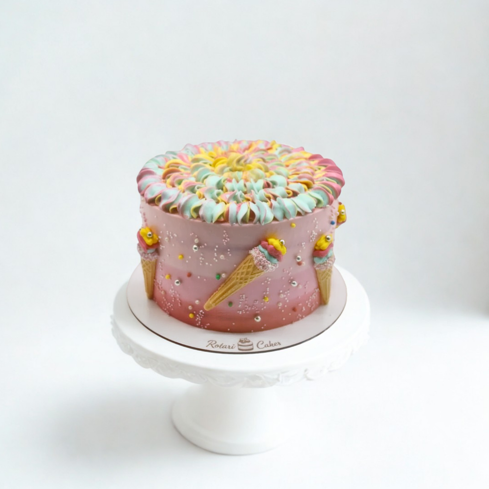 Colorful cake with ice cream cone design on a white stand against a white background