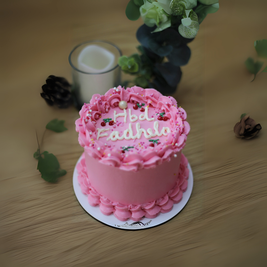Pink Snickers Cake with chocolate sponge, caramel filling, and peanut crunch, topped with a pink design for special occasions.
