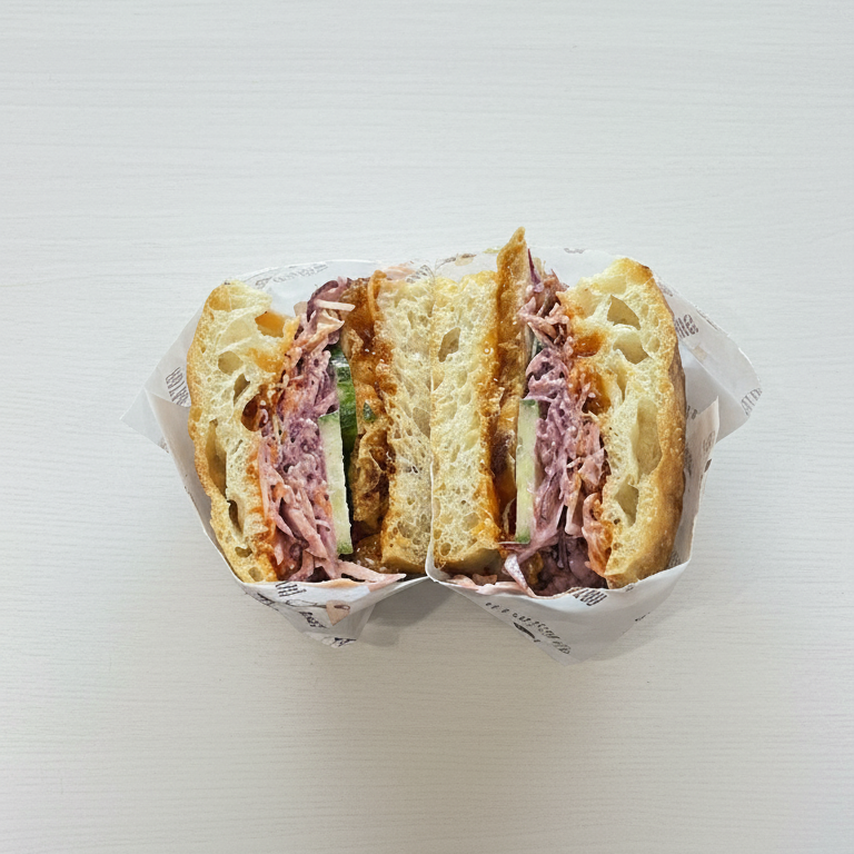 Half-sliced focaccia sandwich in a paper container on a white background
