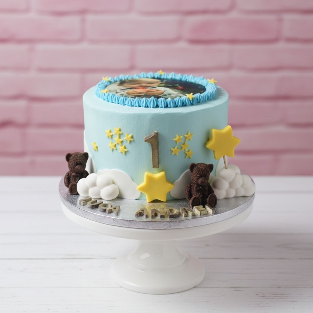 Children's birthday cake with teddy bears, stars, and number '1' on a pink brick background
