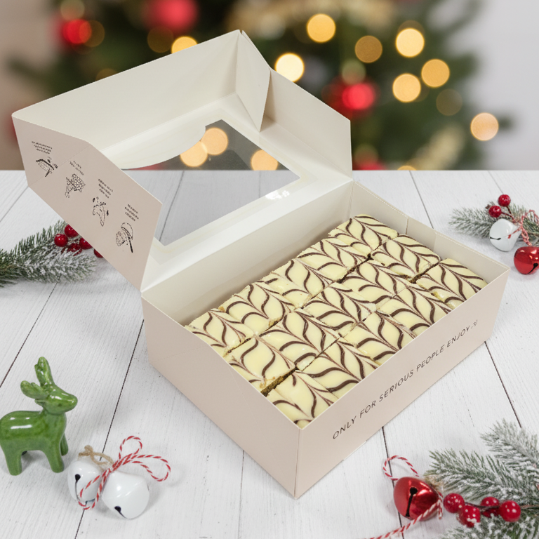 Open box with decorative items on a wooden surface with a blurred Christmas tree in the background.