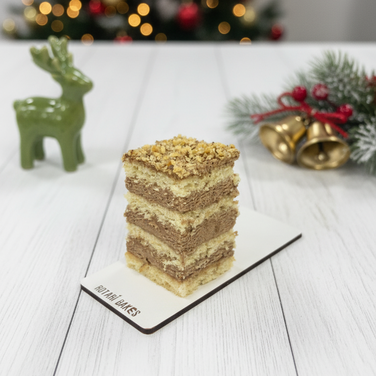
                  
                    Layered cake on a white surface with a Christmas tree in the background
                  
                