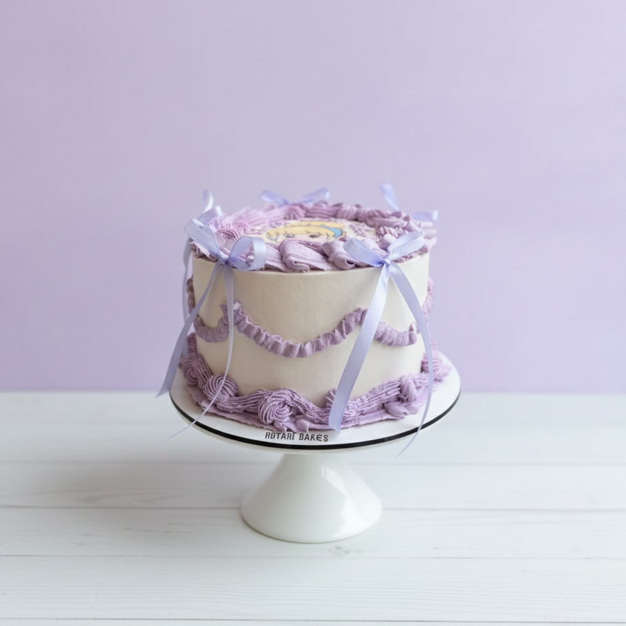 Decorative cindrella cake with purple accents on a white stand against a light purple background