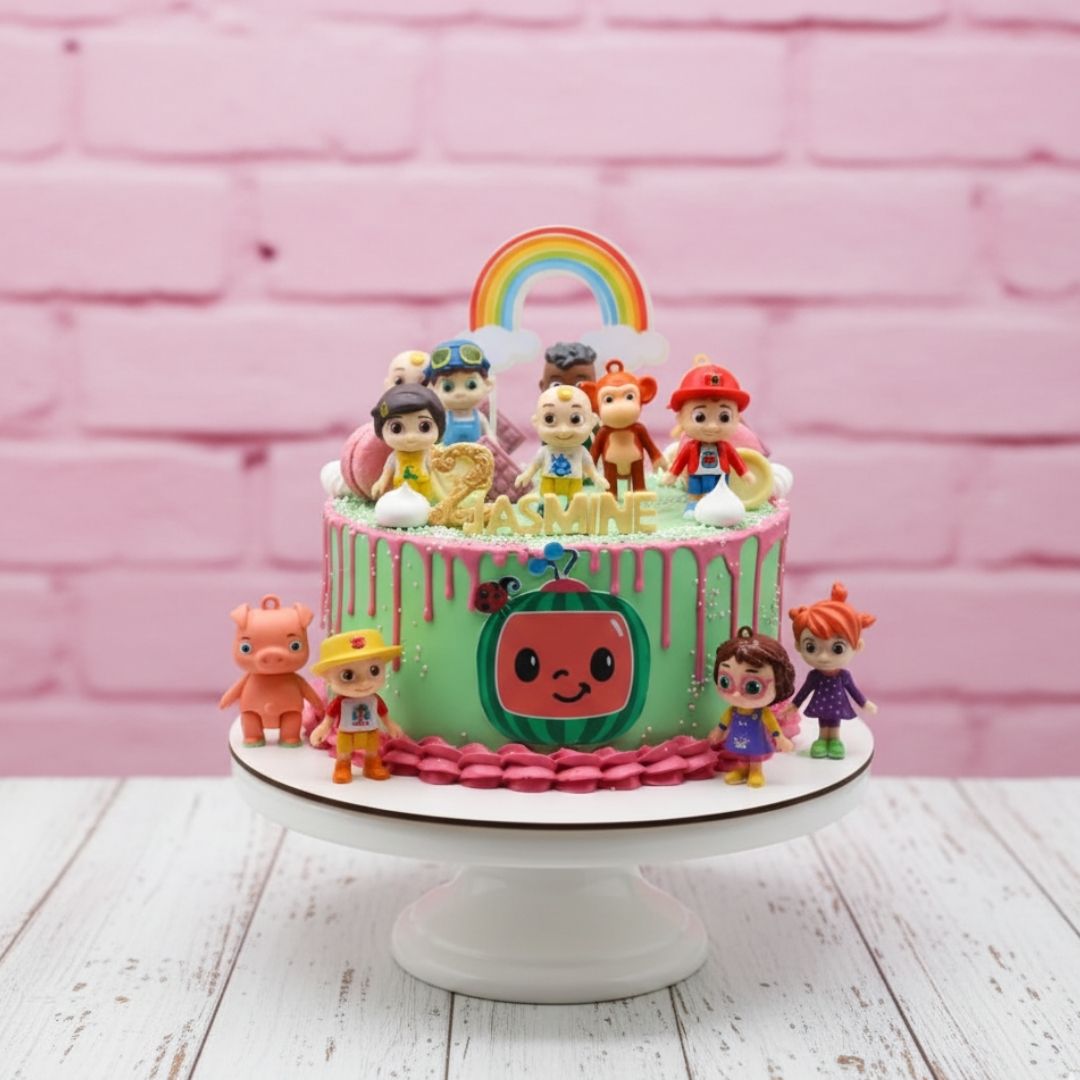 cocomelon theme Children's birthday cake with cartoon character figurines on a pink background