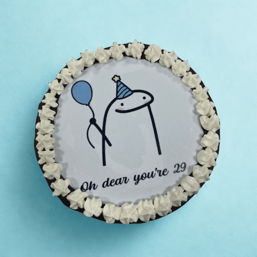 
                  
                    Round cake with white frosting, chocolate border, and birthday-themed design on a light blue background.
                  
                