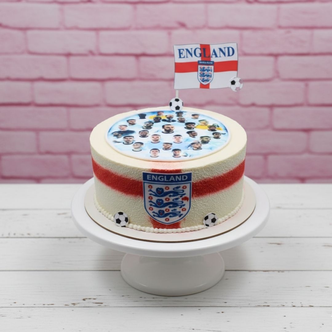 Cake with England football themed decorations including a flag and crest on a pink brick background