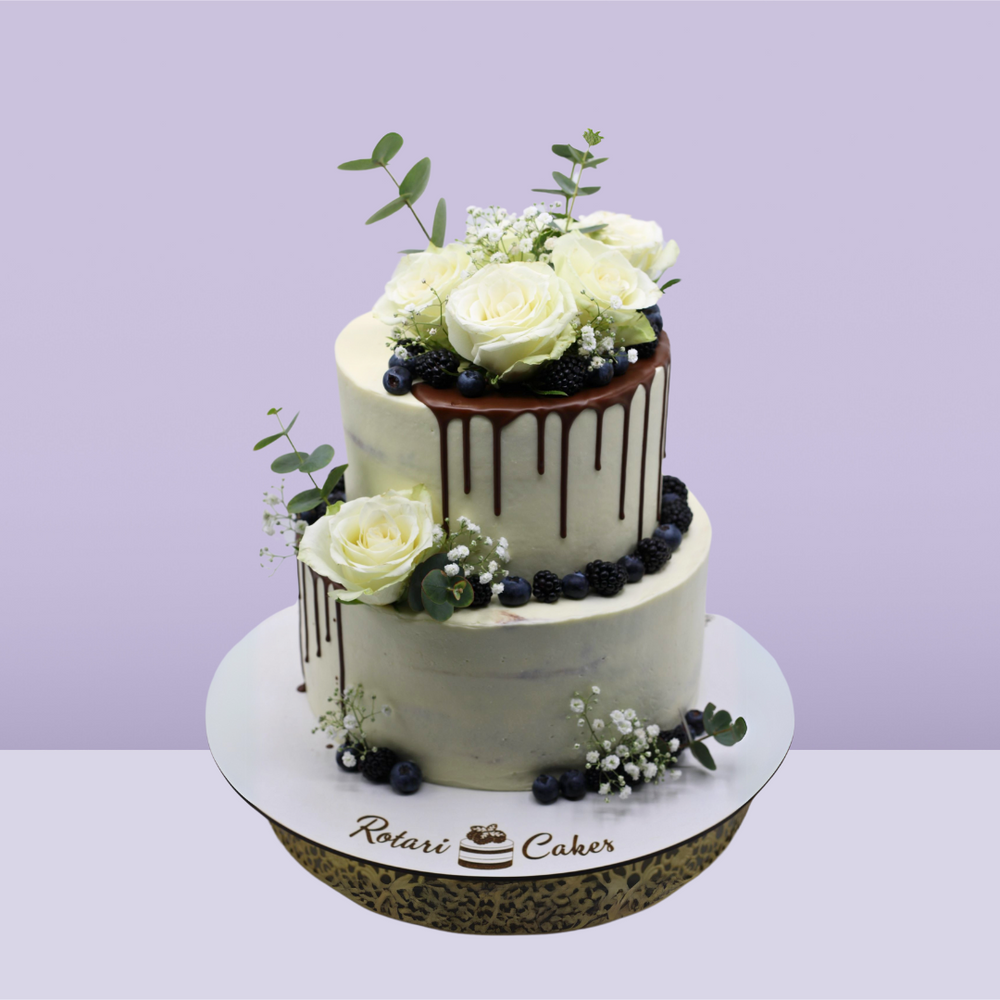 Rustic Semi-Naked Wedding Cake by Rotari Bakes with fresh floral accents and delicate sponge layers, ideal for rustic-themed weddings.
