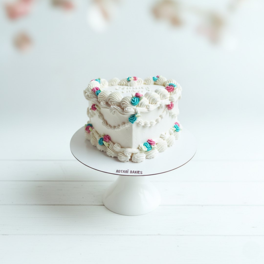 gender reveal cake in heart shape with piping and pink and blue cream