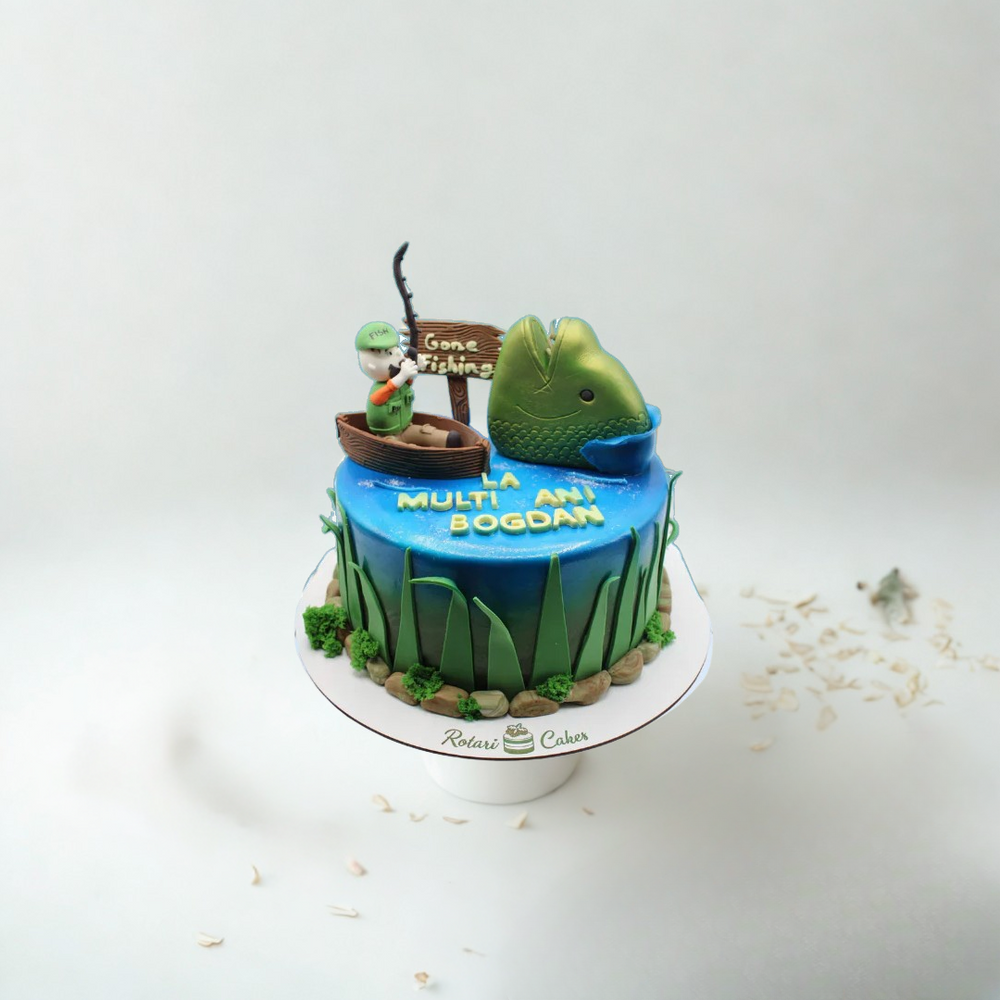 Fishing-themed birthday cake with a fish and fisherman figurine on a white background