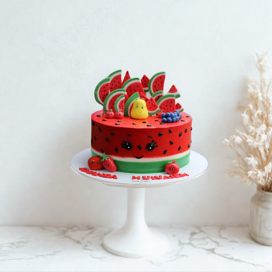 Watermelon-themed cake on a white stand with a white background
