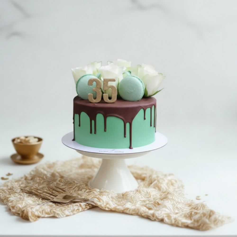 green colour birthday cake with macarons and flowers on top and chocolate drizzled for 35th birthday