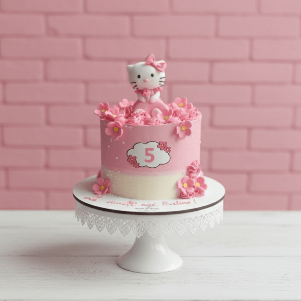 Pink birthday cake with Hello Kitty figure against a pink brick wall.