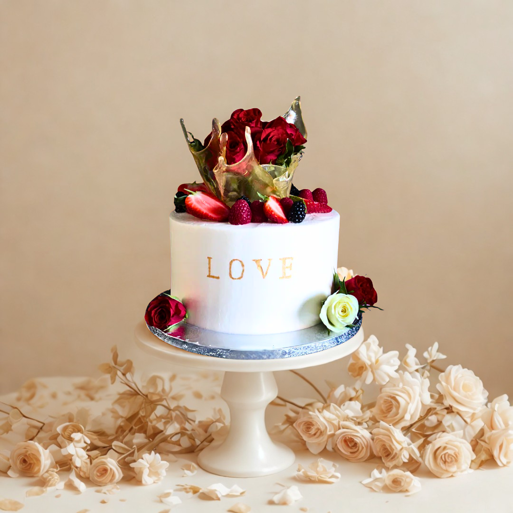 White cake with 'LOVE' on top, decorated with flowers and strawberries