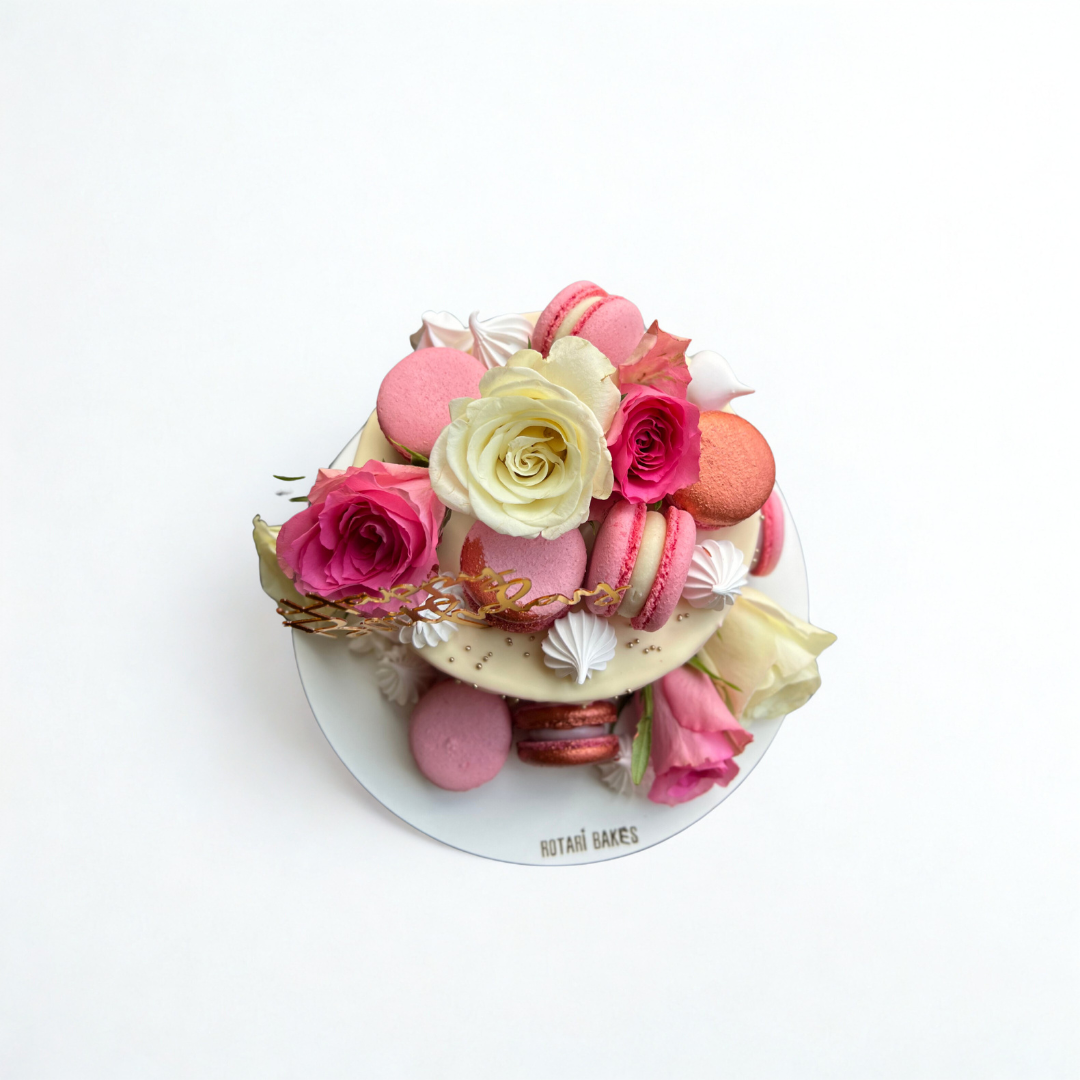 Decorative cake with pink and white flowers and macarons on a white background