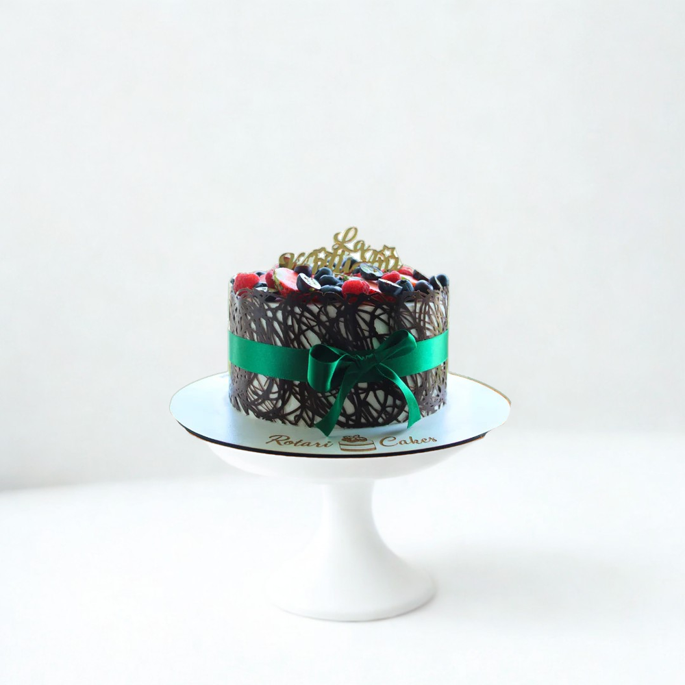 Decorative cake with a green ribbon on a white stand against a white background