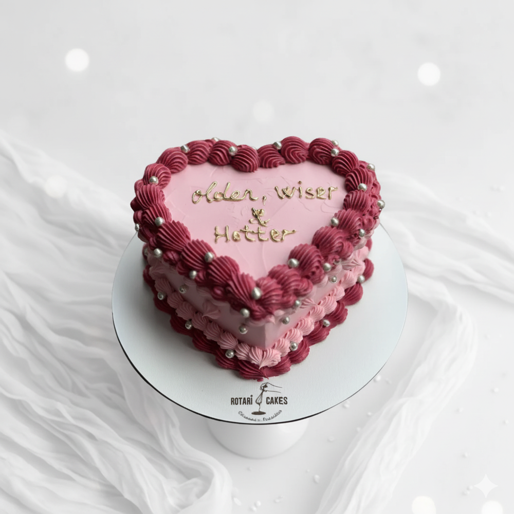 Heart-shaped cake with pink and red frosting on a white background