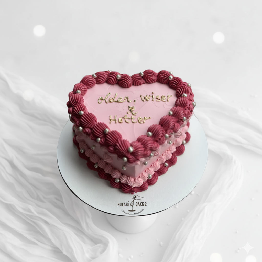 Heart-shaped cake with pink and red frosting on a white background