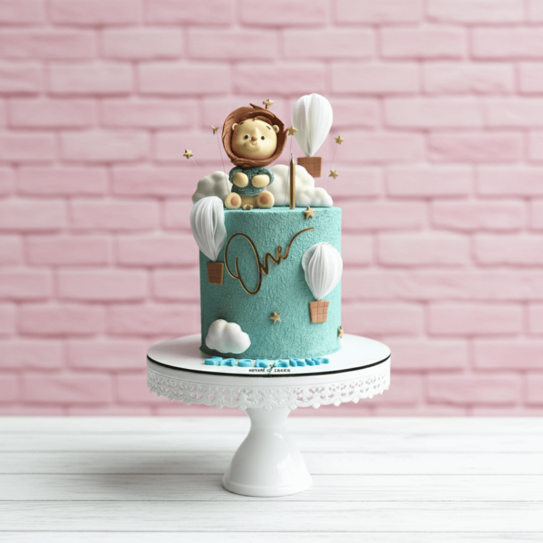 Decorative cake with a lion figurine and hot air balloons on a pink brick wall background
