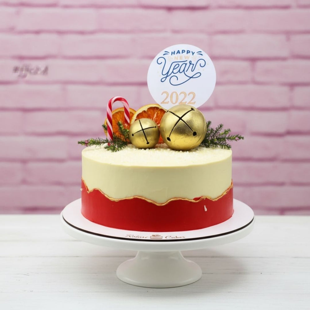 New Year's cake with gold bells and candy canes on a pink brick background
