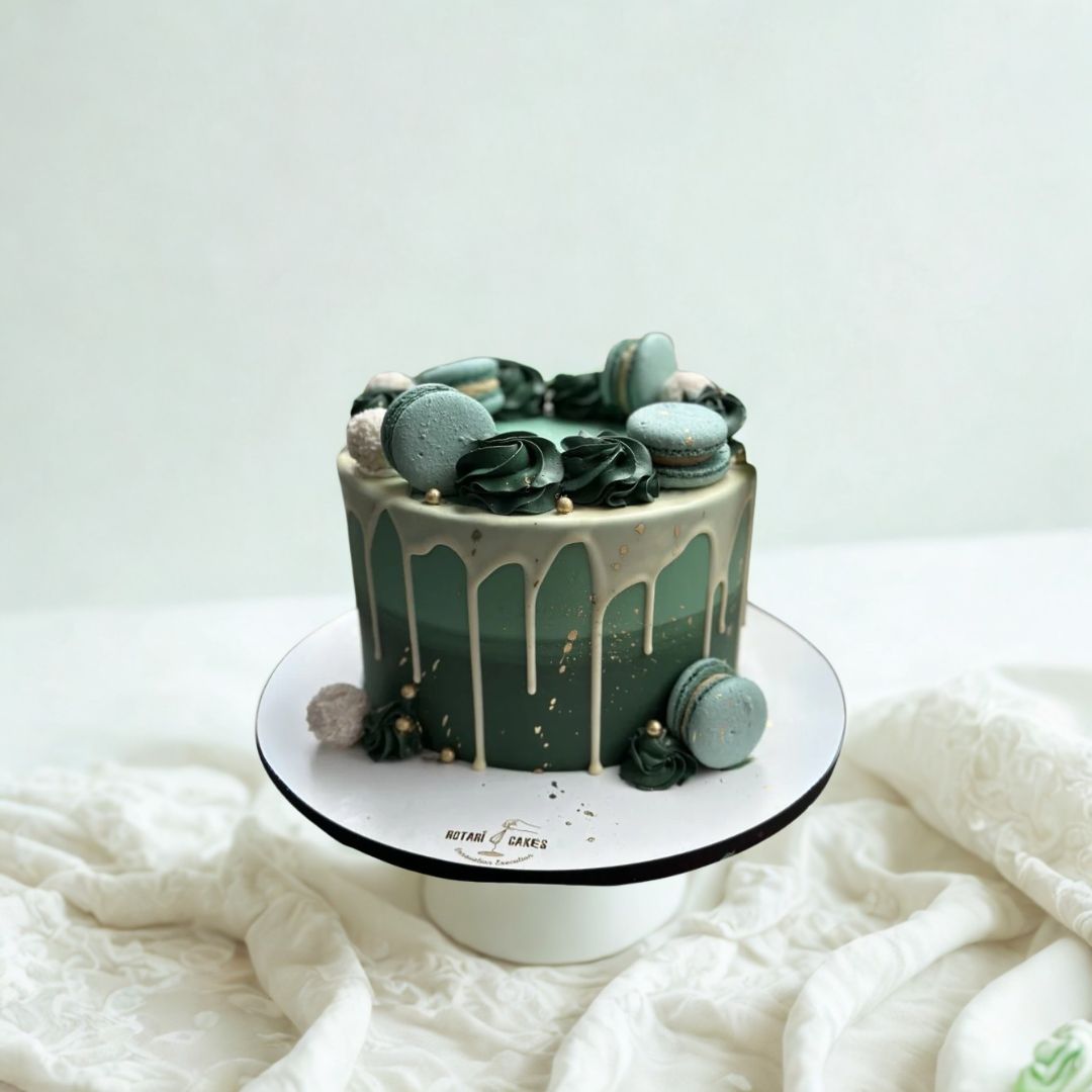 green ombre cake with macarons on top of the cake