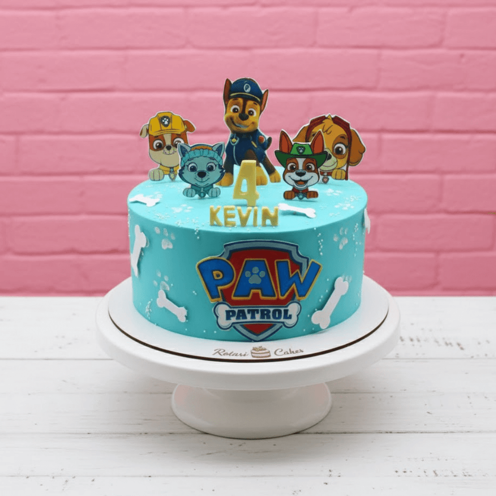 Paw Patrol birthday cake with cartoon characters on a pink brick wall background