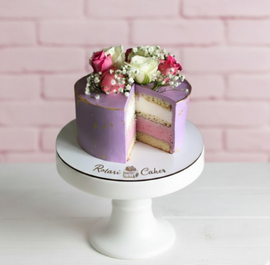 Decorative cake with flowers on a white stand against a pink brick wall