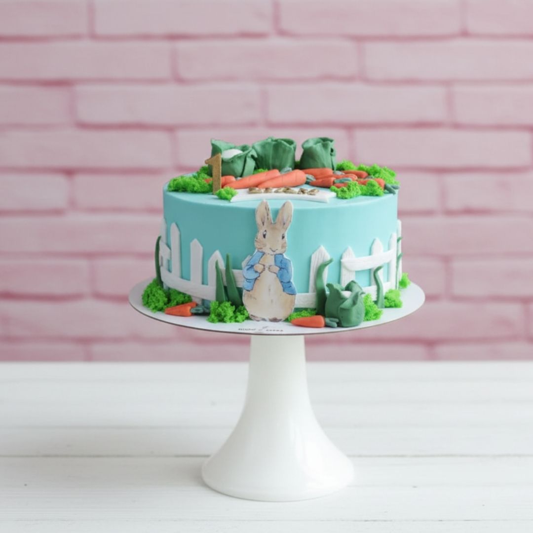 Cake with a rabbit design and garden elements on a white stand against a pink brick wall.