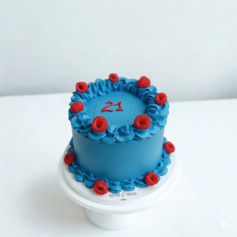 
                  
                    Blue cake with red decorations on a white stand against a white background
                  
                