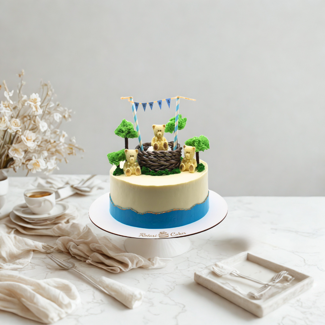 Decorative cake with teddy bear figurines on a white tablecloth.