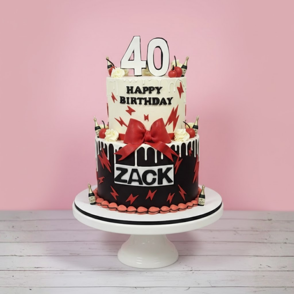 Birthday cake with 'Happy Birthday Zack' on a white stand against a pink background