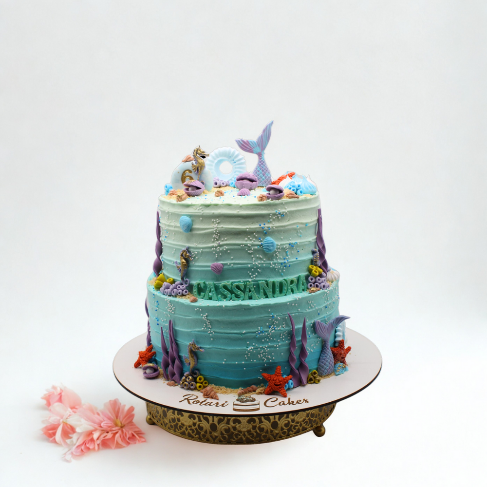 Two-tiered cake with ocean-themed decorations on a white background