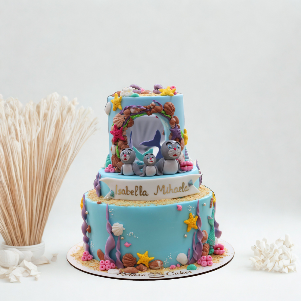 Two-tiered cake with ocean-themed decorations on a white background