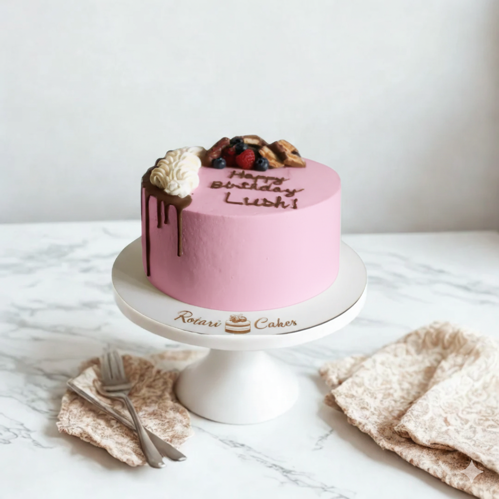 
                  
                    Pink birthday cake with fruit toppings on a white marble surface, featuring the brand 'Rotary Cakes'.
                  
                