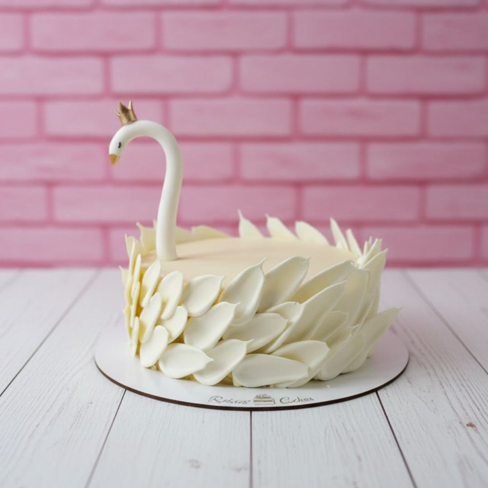 Swan-shaped cake with white feathers and a pink brick background