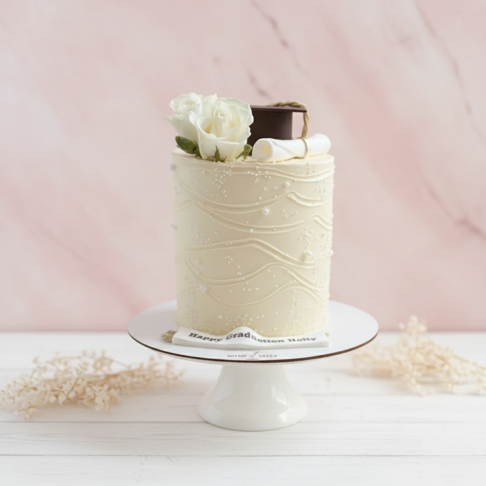 White Graduation Cake with graduation hat and diploma on top for graduation celebration