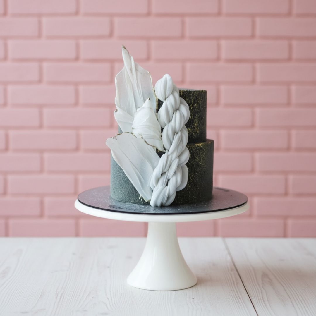 Decorative cake with white feather-like decorations on a pink brick wall background